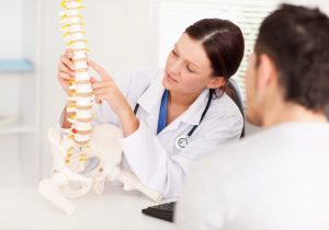 A female doctor is pointing on a bone in the spine